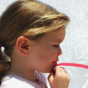 Kind, das über Papierstreifen pustet - Physik Experiment zum Bernoulli-Effekt